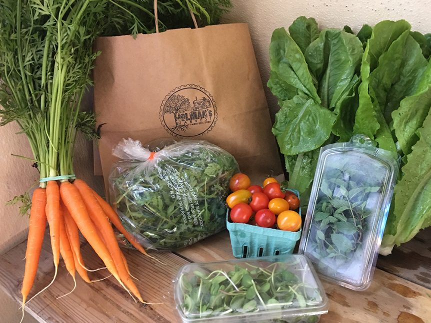 A variety of vegetables are sitting on a wooden table.