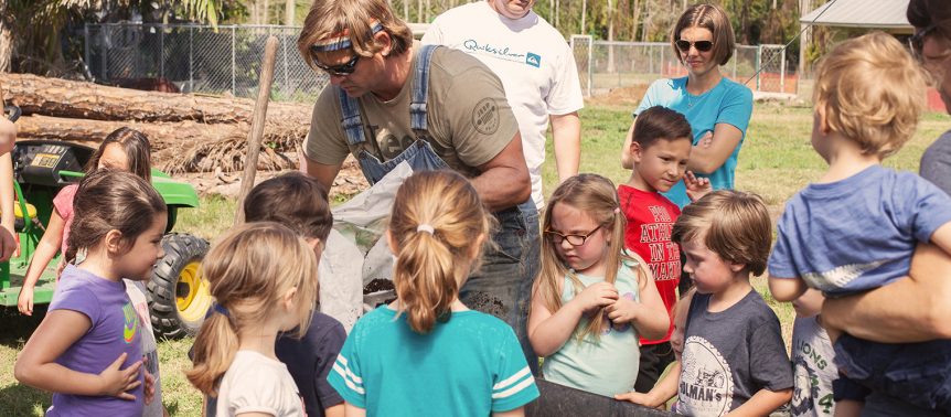 A group of children gathered around a tractor.